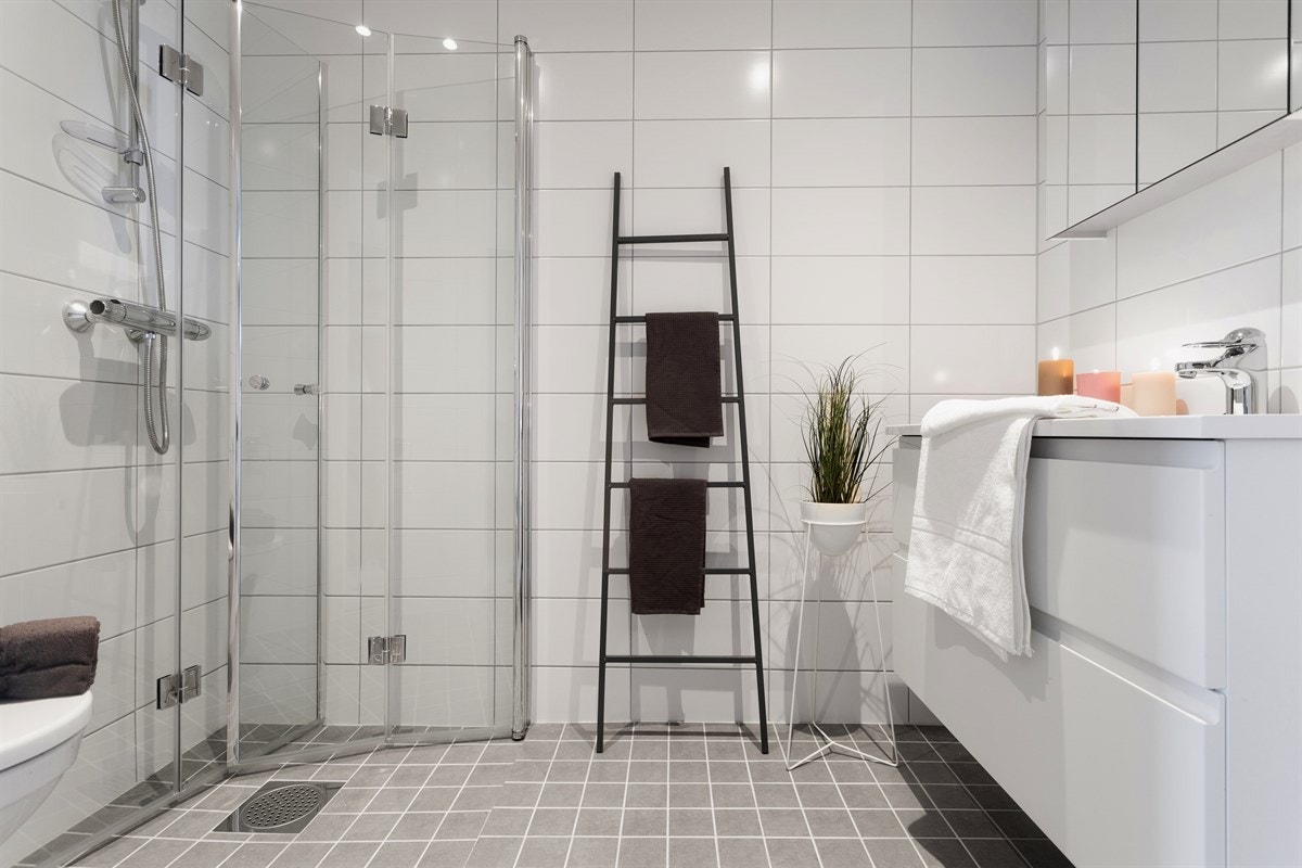 Bad fra soverom med foldbare dusjdører i glass, varmekabler i gulv, vegghengt toalett, dowlights i tak, servant med underskap og speilskap over servant. Galleribilde