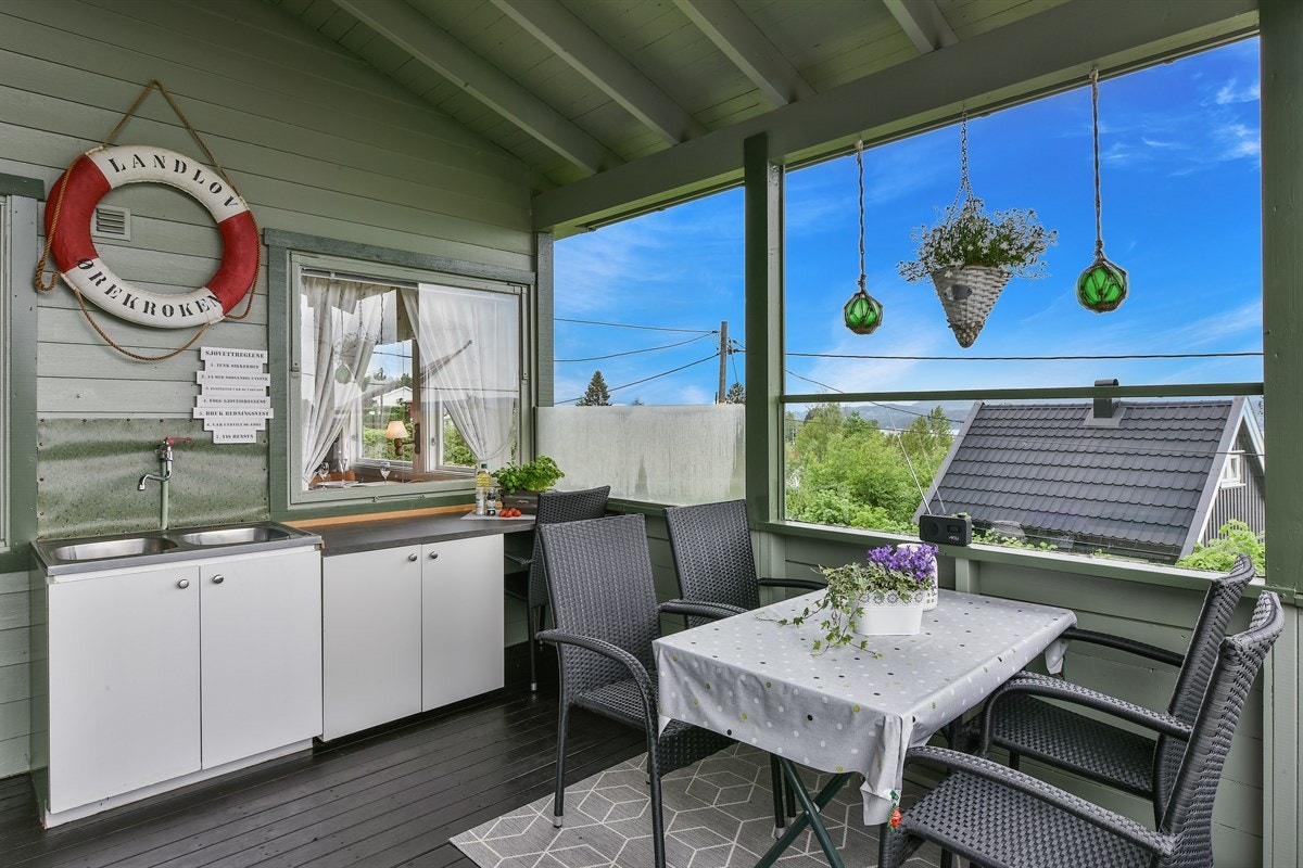 På verandaen er det et utekjøkken med dobbelservant, tappested for kaldt vann, flere benkeskap og laminatbenkeplate. Galleribilde