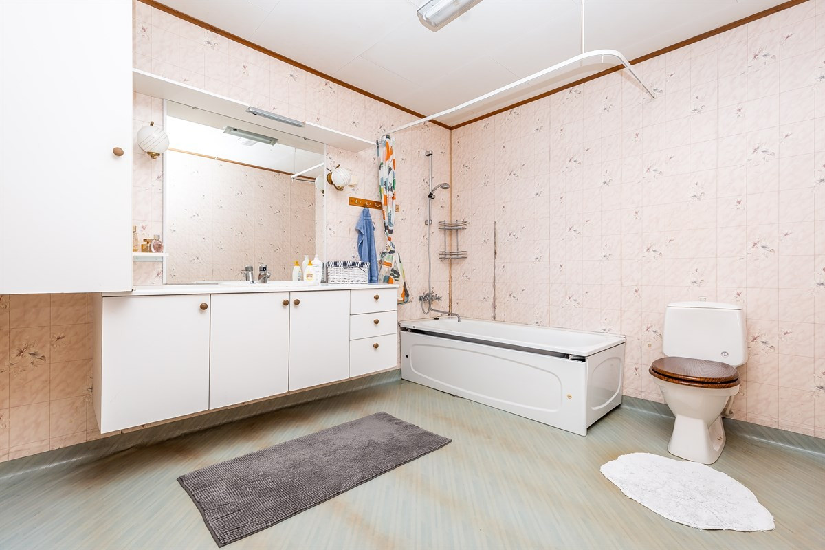 Romslig og lyst bad med wc, servant med speil og badekar. Varmekabler i gulv