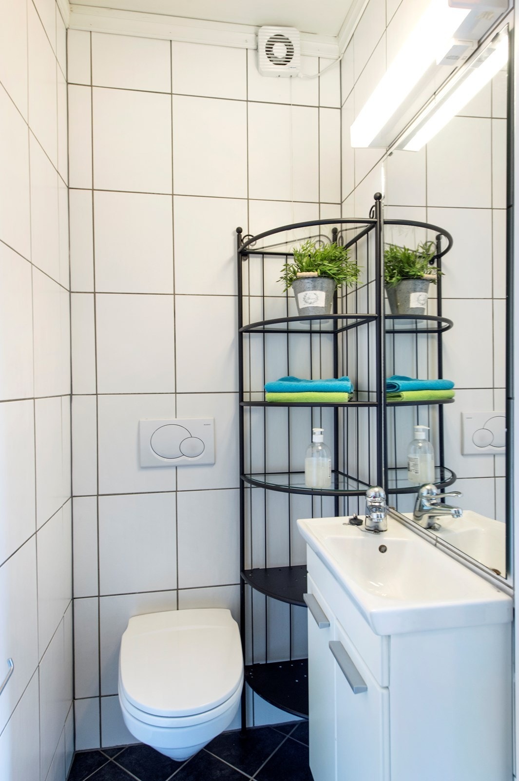 Det inneholder dusj med skyvedører, vegghengt toalett, servant med innredning, speil og belysning. Galleribilde