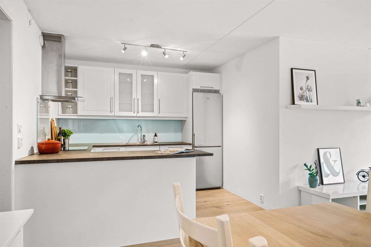 Svært lekker og klassisk kjøkkeninnredning med hvite profilerte fronter og vitrinedører. Galleribilde