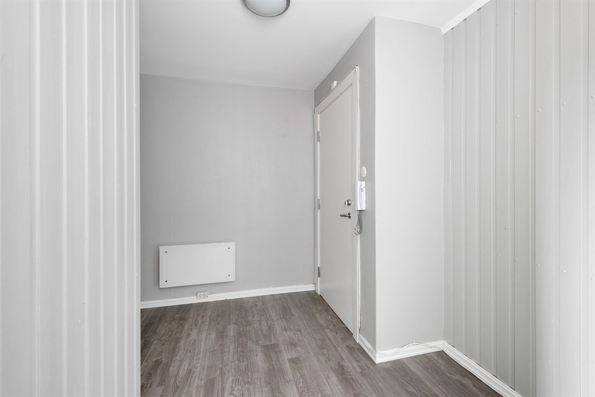 Entreen har askegrå laminat på gulv og veggene er gråmalte, med ulik struktur. Galleribilde