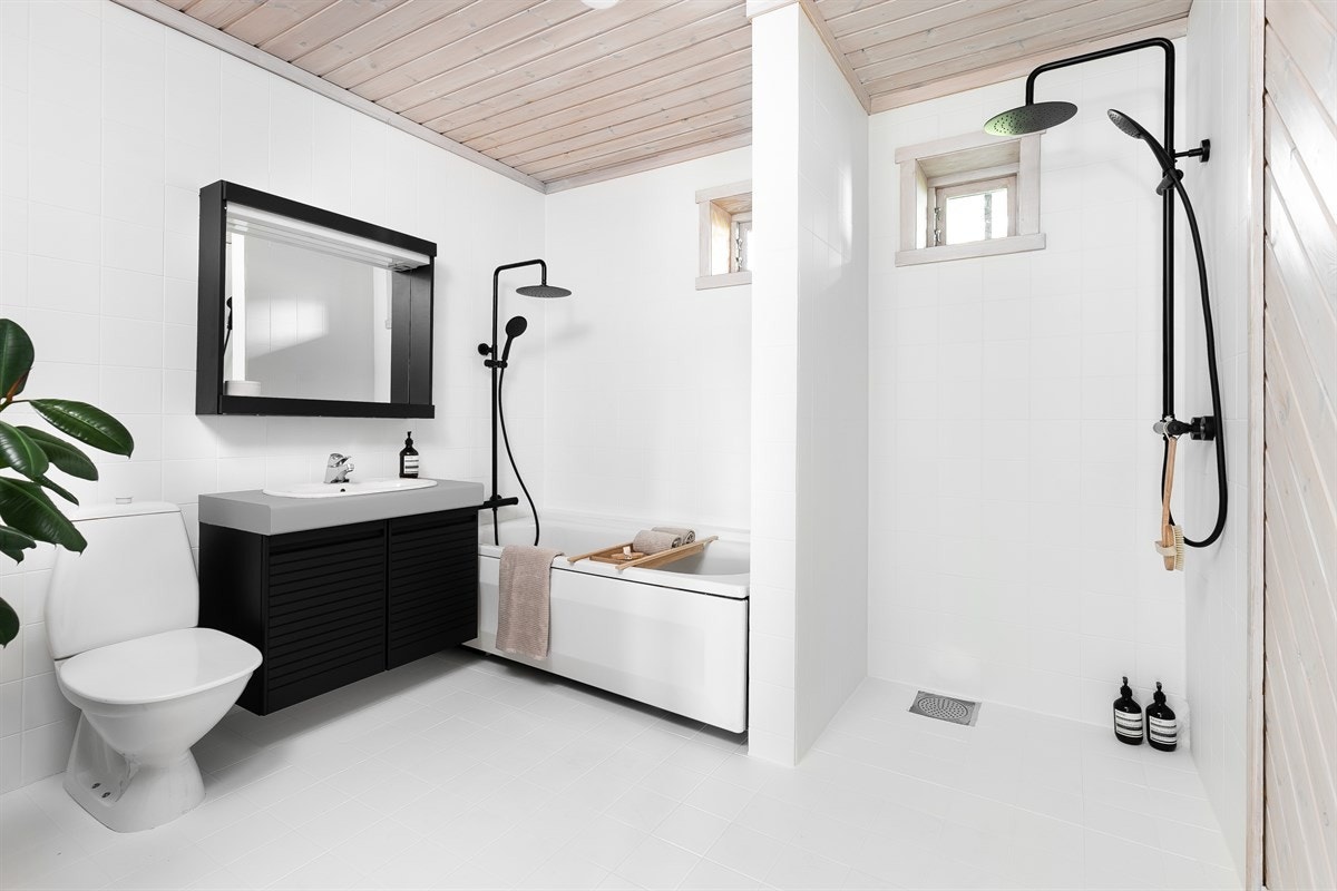 Det andre badet har adkomst fra peisestuen i underetasjen og gir et behagelig inntrykk med hvitmalte gulv og veggfliser, samt varme i gulv og trehvitt takpanel med lyskuppel. Galleribilde