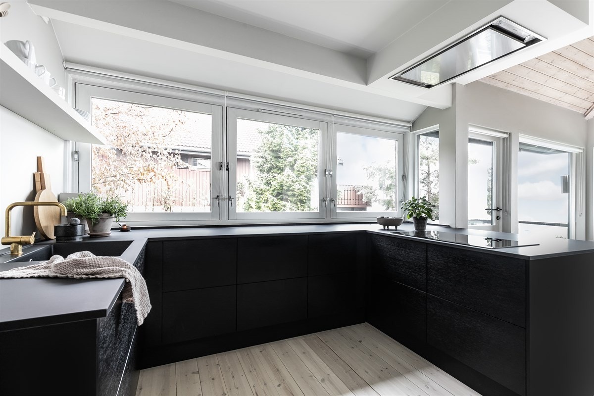 Innredningen fra JKE Design har glatte, håndtaksløse eikefronter i sort med push-funksjon, samt laminatbenkeplate med integrert oppvaskkum i kompositt og to pop-up strømsøyler. Galleribilde