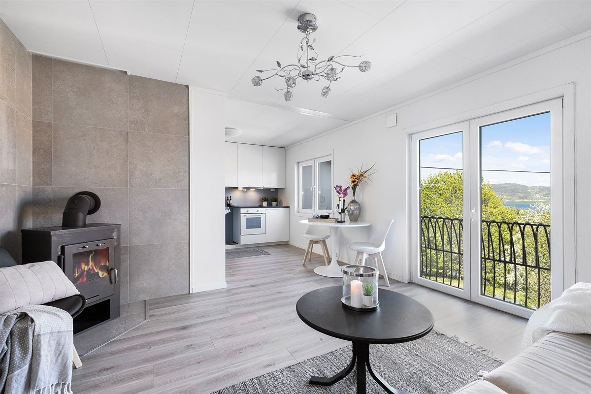 I hjørnet er det to brannvegger med grå fliser, bak en koselig peisovn. Når det gjelder møblement er det god plass for sofa, godstoler og et spisebord. Galleribilde