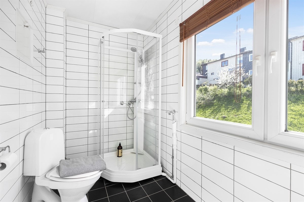 Badet ligger ved entreen og har adkomst via en dør fra 2019. Selve badet ble oppusset i 2011 og har gulvvarme, svarte gulvfliser, hvite veggfliser og to vinduer som gir rikelig med dagslys. Galleribilde