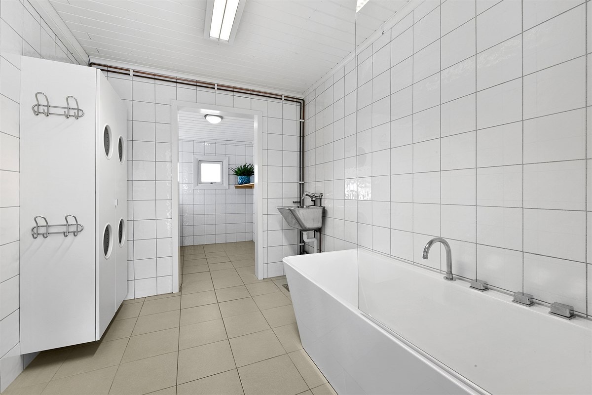 Det romslige badet i første etasje ble totaloppusset i 2013. Badet er delikat med hvite veggfliser og gulvfliser i en fin, nøytral sandfarge. Galleribilde