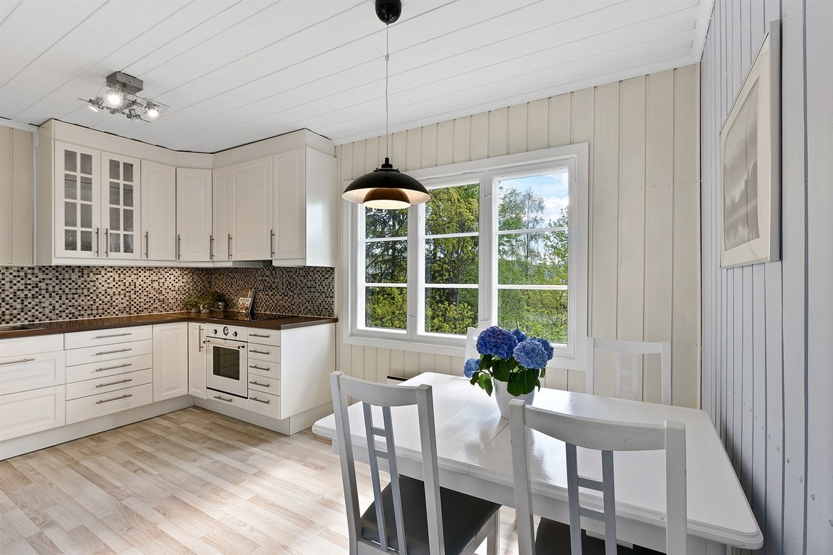 Ikea-innredningen fra 2011 er pen med hvite, profilerte fronter, vitrineskap og laminatbenkeplate med oppvaskkum i stål. Galleribilde