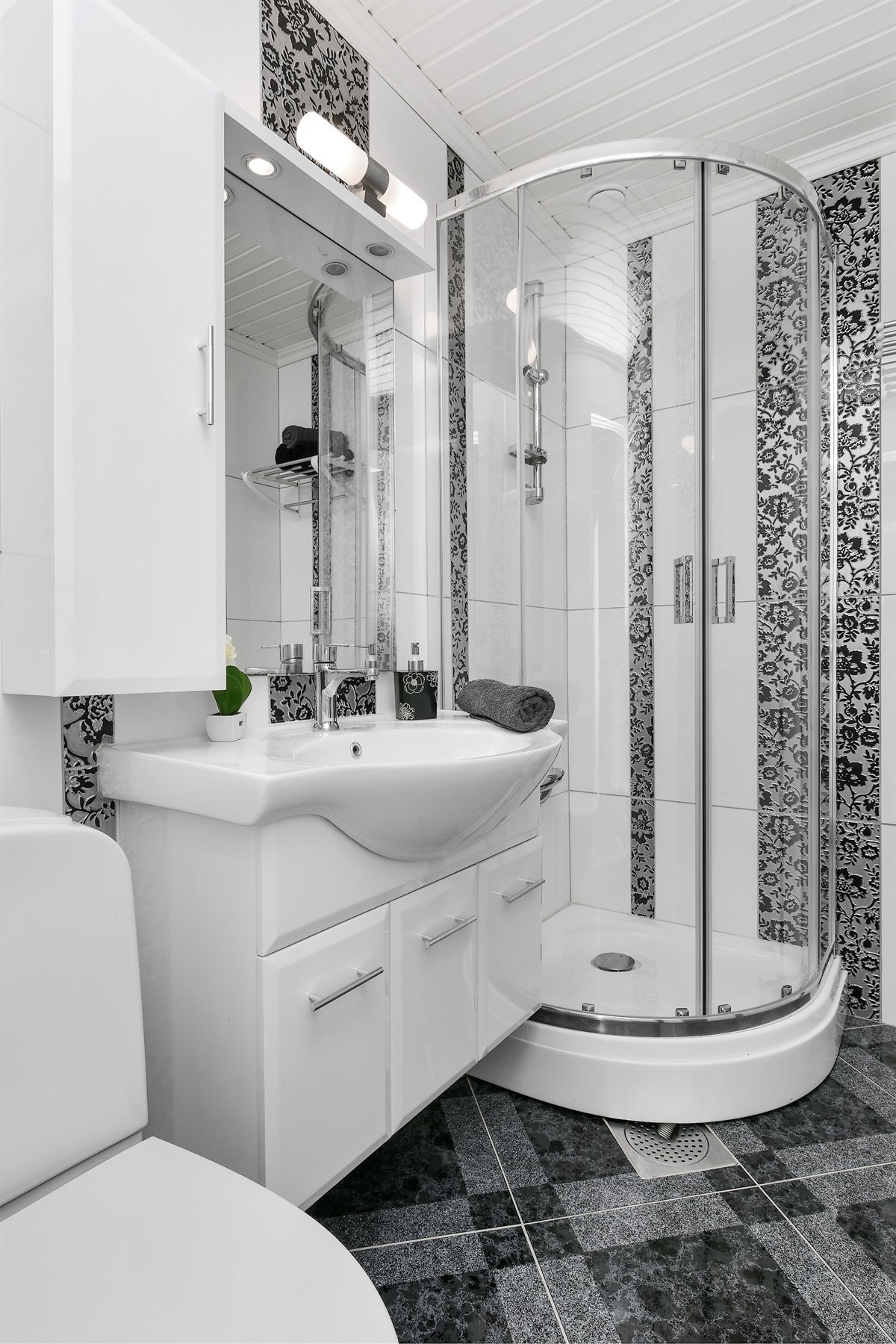 Det er dusjkabinett, og innredningen har hvite, slette fronter, heldekkende servant og speil med belysning. Galleribilde