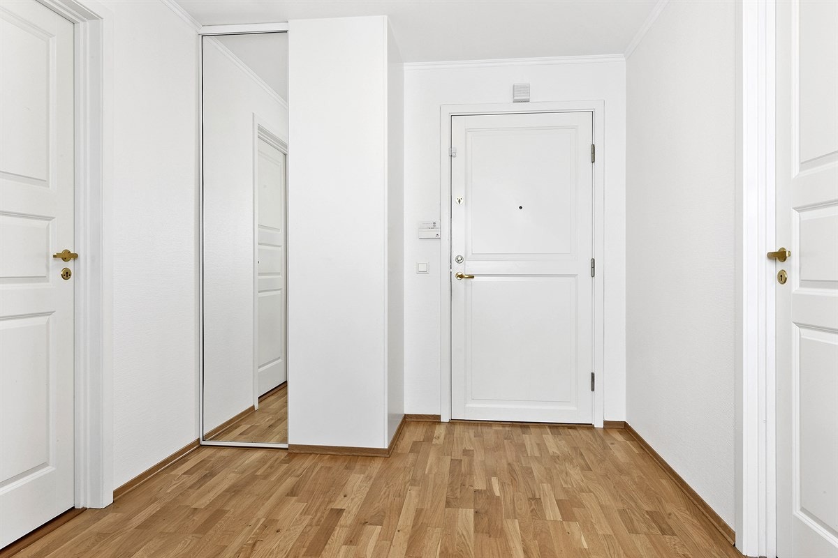 Entreen er praktisk innredet med bl.a. trestavs parkettgulv, skyvedørsgarderobe med speilfront og hvitmalte vegger. Galleribilde