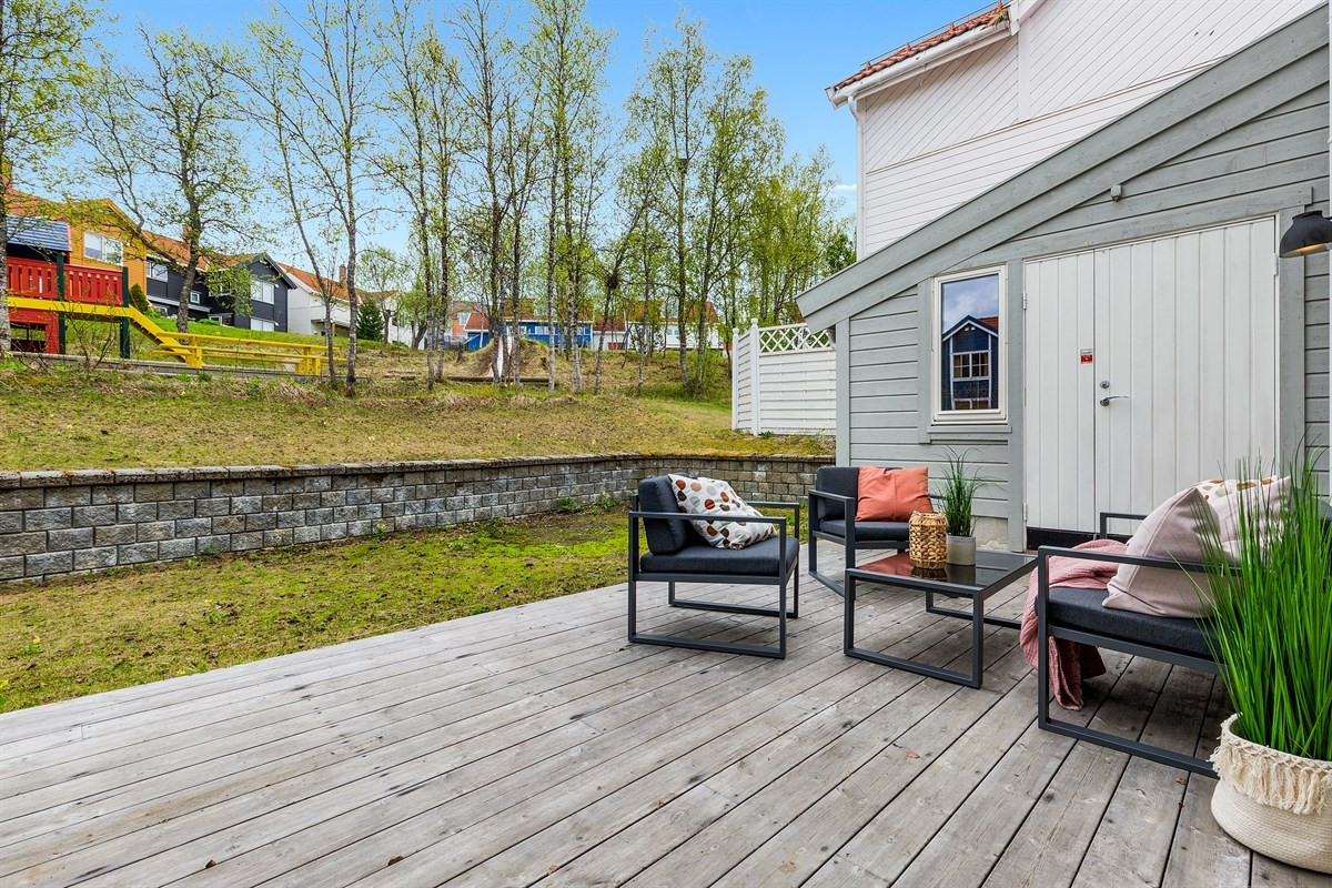 Østvendt terrasseplatt fra stue i 1. etasje, kun et steinkast unna lekeplass! Gangdør til 2 boder i garasje fra terrasse