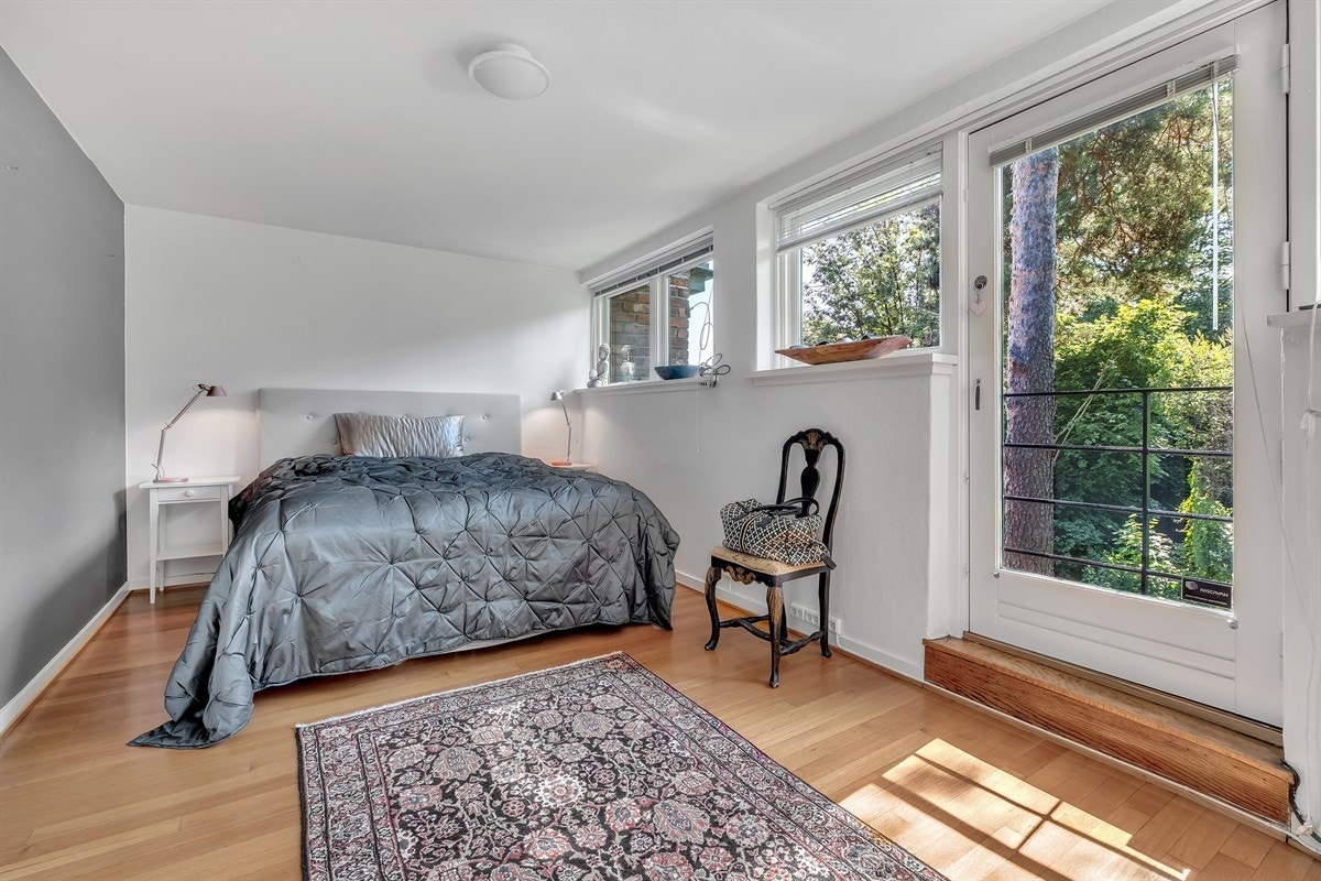 Hovedsoverom med vinduer og fransk balkong vendt ut mot den grønne og hyggelig hagen Galleribilde