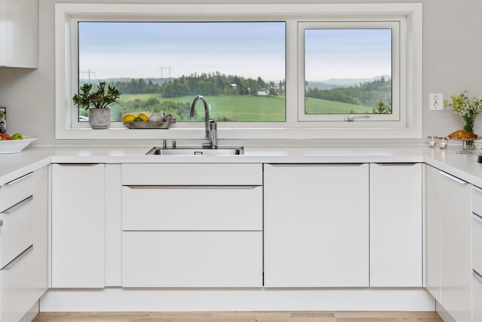 Benkeplaten er i laminat og hvit, som resten av innredningen og har underlimt vaskekum i flukt med vinduet Galleribilde