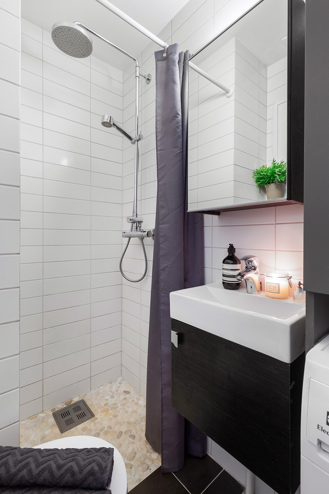 Badet inneholder dusjhjørne, vegghengt wc, servant med skap, speil og oppbevaringsskuffer. Galleribilde