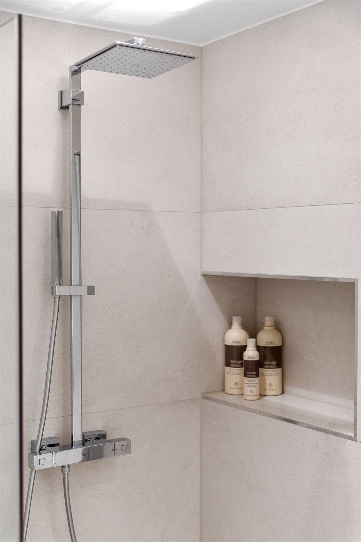 Veggmontert dusj med hodedusj og hånddusj i nisje med vendbare dører Galleribilde