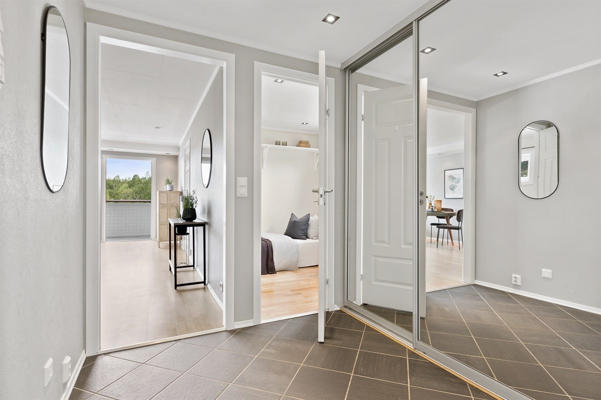 Innbydende inngangsparti med stor skyvedørsgarderobe med speilfront og ellers plass til møblement. Galleribilde