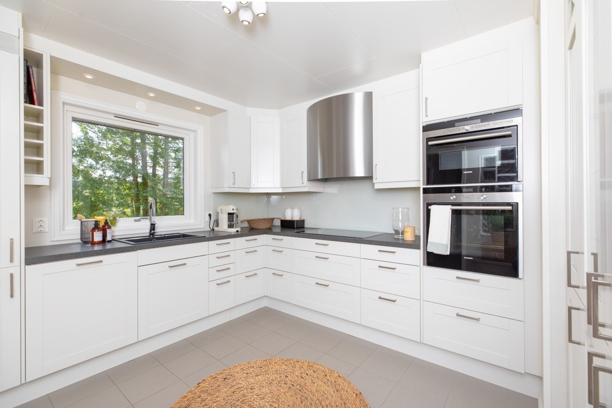 Tidløs kjøkkeninnredning fra Sigdal med laminerte benkeplater og takhøye overskap. Galleribilde