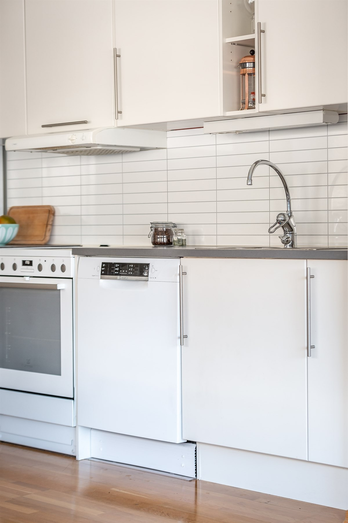 Lyse glatte flater på kjøkkeninnredning, opplegg for oppvaskmaskin og kitchenboard over benk