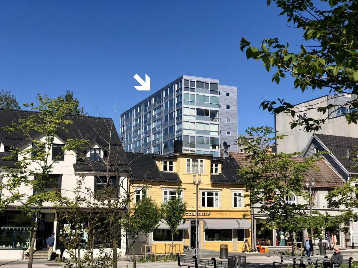 Stor toppleilighet med vedfyring og garasje i Sentrum Terrasse. Bildet er tatt fra kirkeparken i sentrum og viser leilighetens nærhet til gågata.