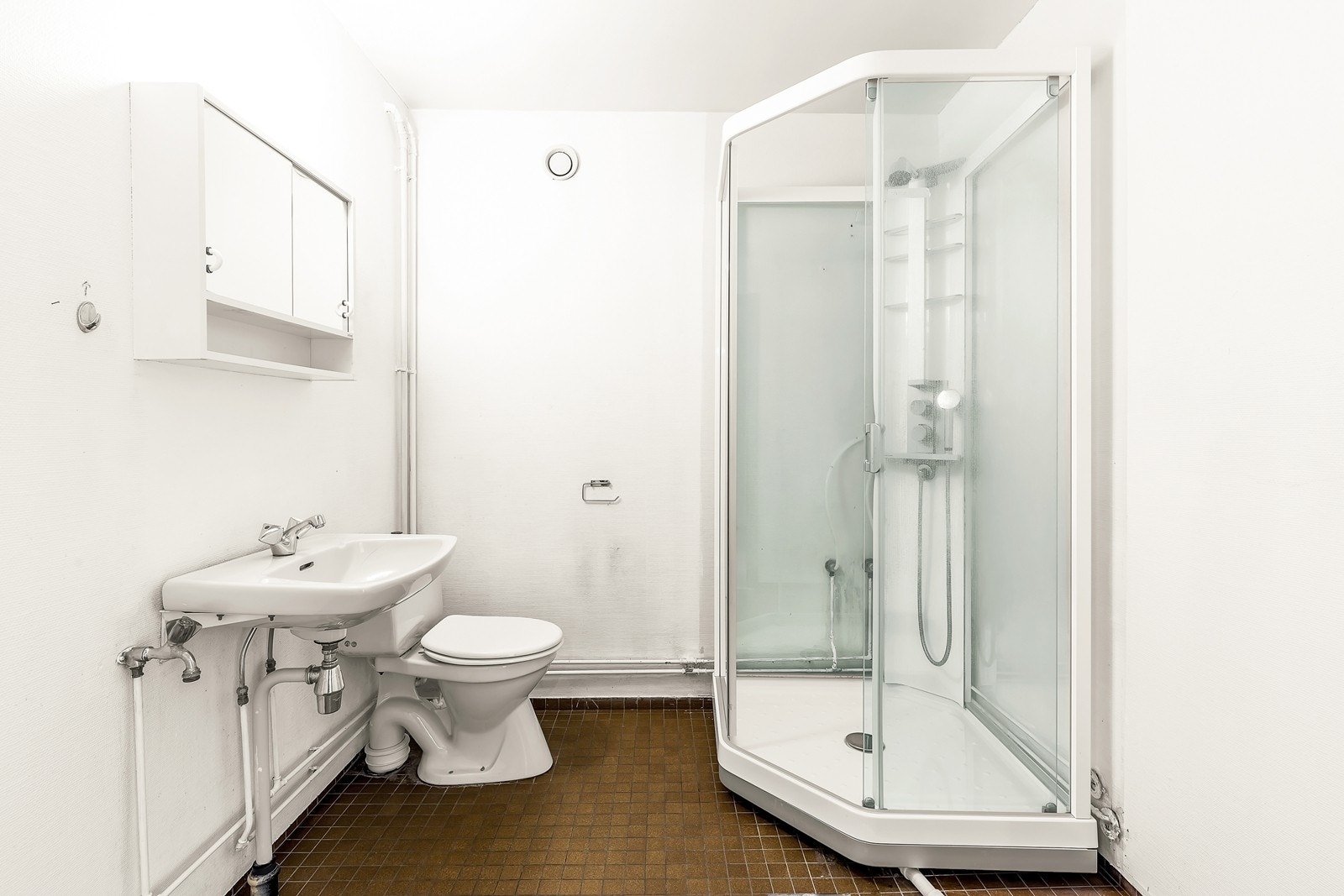 Bad med gulvmontert toalett, servant og dusjkabinett. Galleribilde