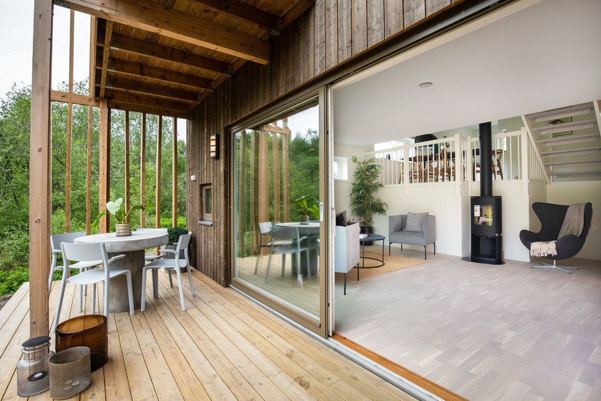 Utgang til en særdeles hyggelig terrasse med platting og bred skyvedør Galleribilde