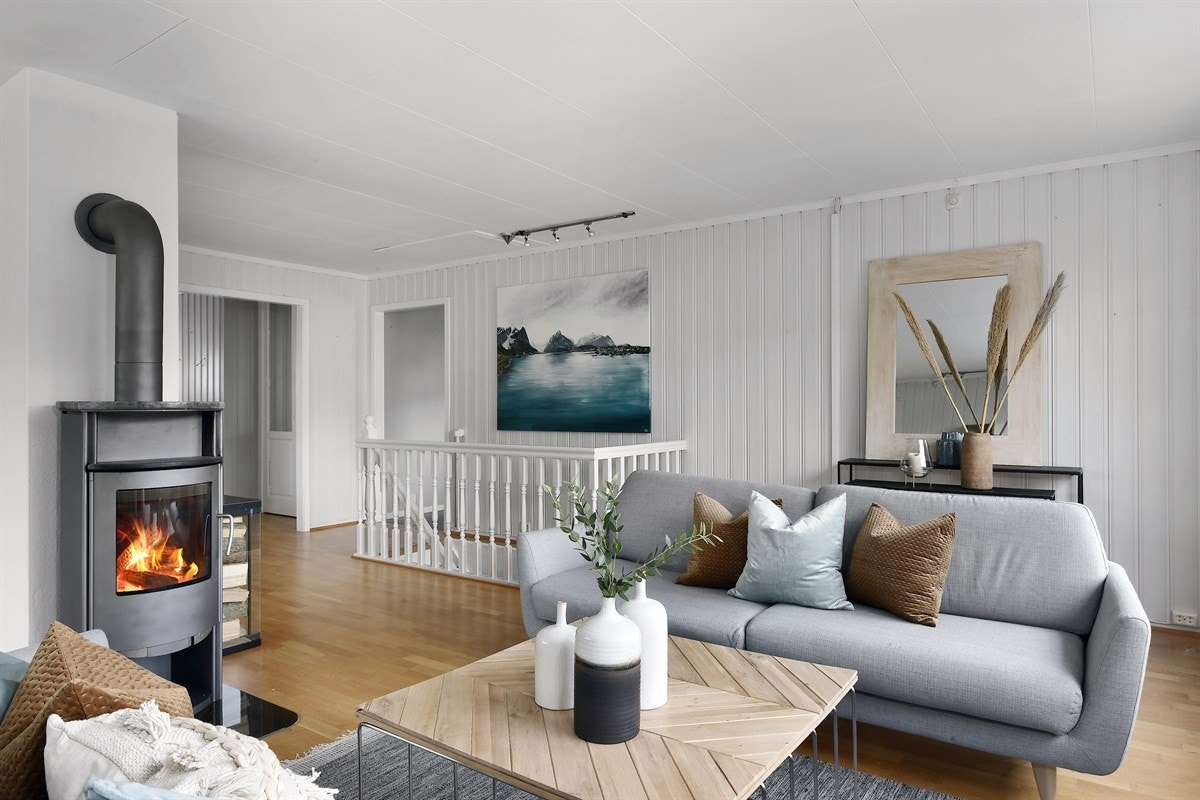 Stuen har lysmalt panel og brystningspanel, på gulvet er det parkett. Det er åpent mot entreen og trapp ned til kjellerstuen. Galleribilde