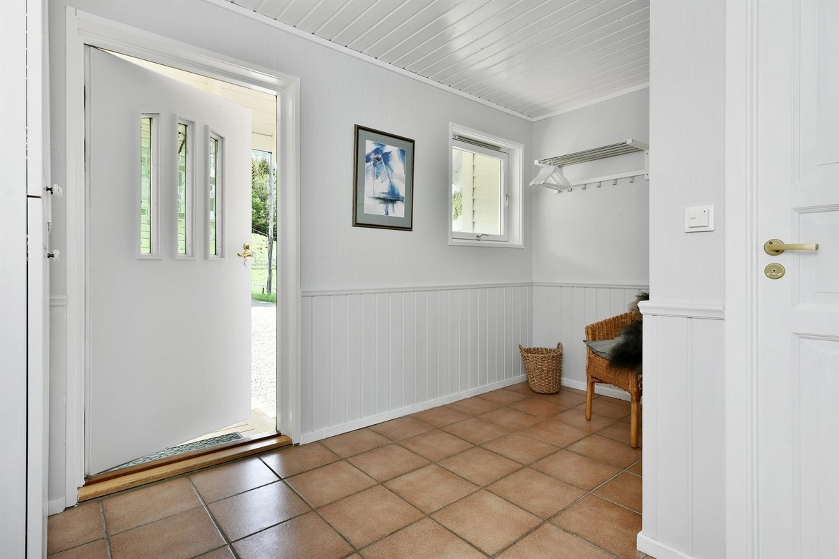 Entreen har lysmalte veggflater og fliser på gulv med behagelig gulvvarme. Galleribilde