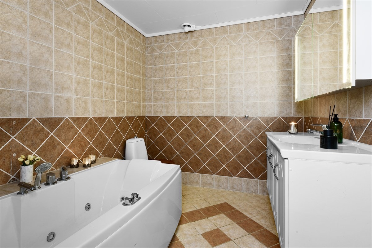 Det ene badet ligger i første etasje og har fliser på gulv og vegger. Galleribilde
