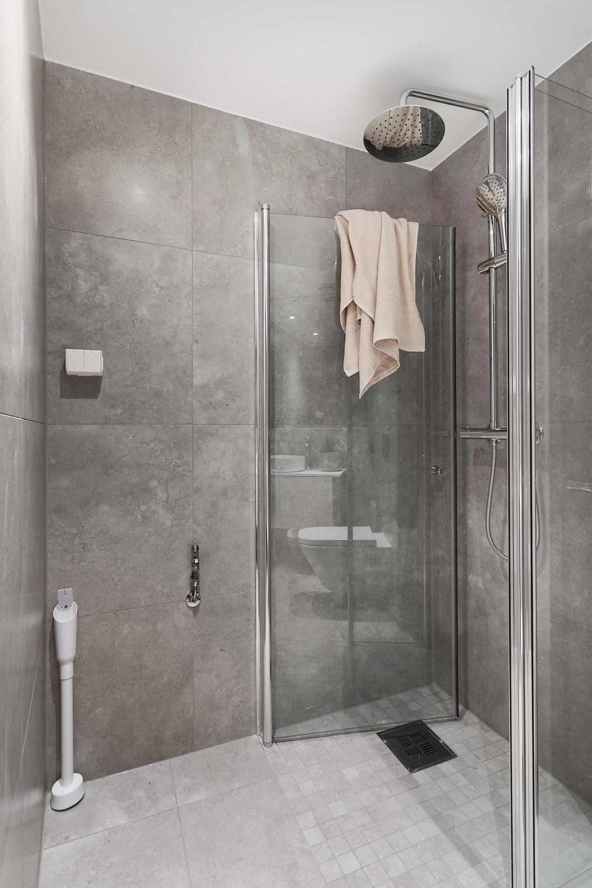 Lekkert bad med varmekabler, betongflis på gulv, mosaikk i dusjsonen, limt speil på hel vegg, dusj med svingbare dusjdører i glass, veggmontert wc, servant på benkeplate samt opplegg for vaskemaskin. Galleribilde