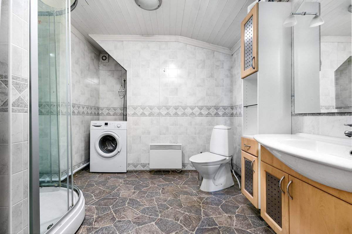 Romslig bad i 2. etasje er innredet med wc, dusjkabinett, servant med skap og speil, samt opplegg til vaskemaskin
