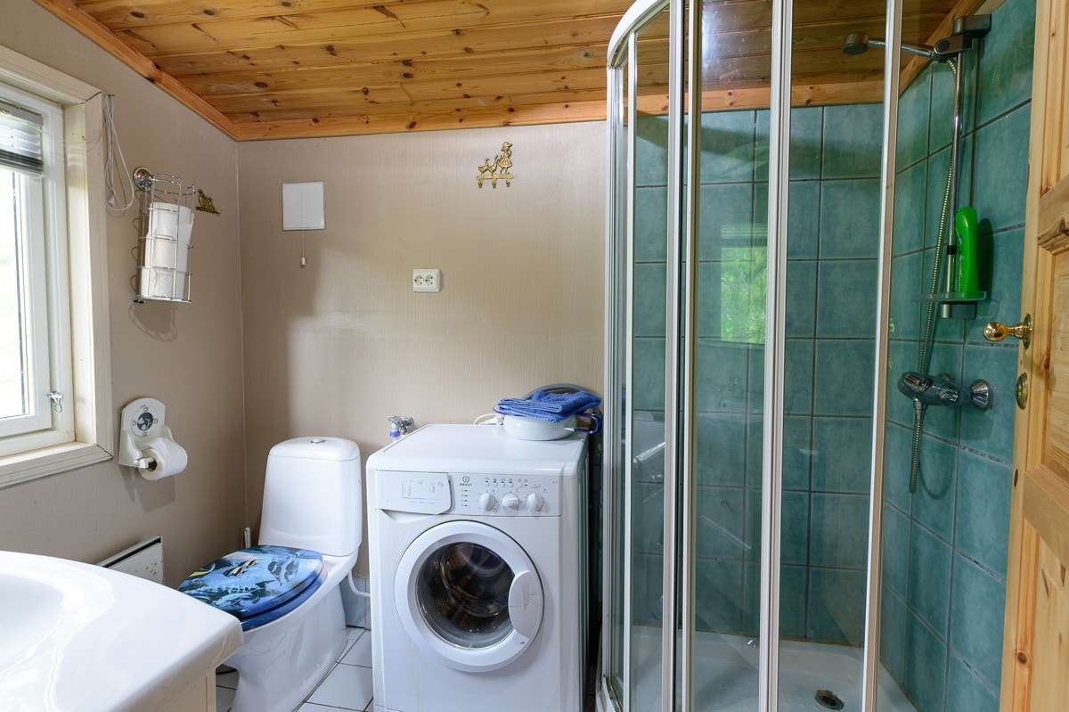 Bad med fliser på gulv og opplegg for vaskemaskin. Galleribilde