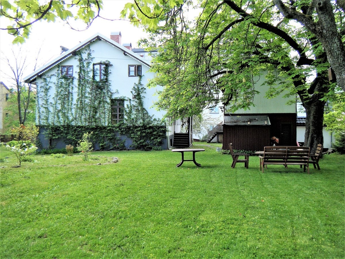 Del av den store, vakre haven. Huset sett fra haven med stallbygningen til høyre for huset. Galleribilde