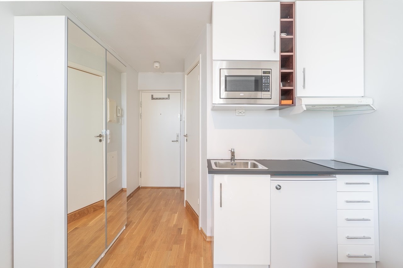 Det står et garderobeskap mellom stuen og entréen for oppbevaring. Skapet fungerer som en naturlig avdeler Galleribilde