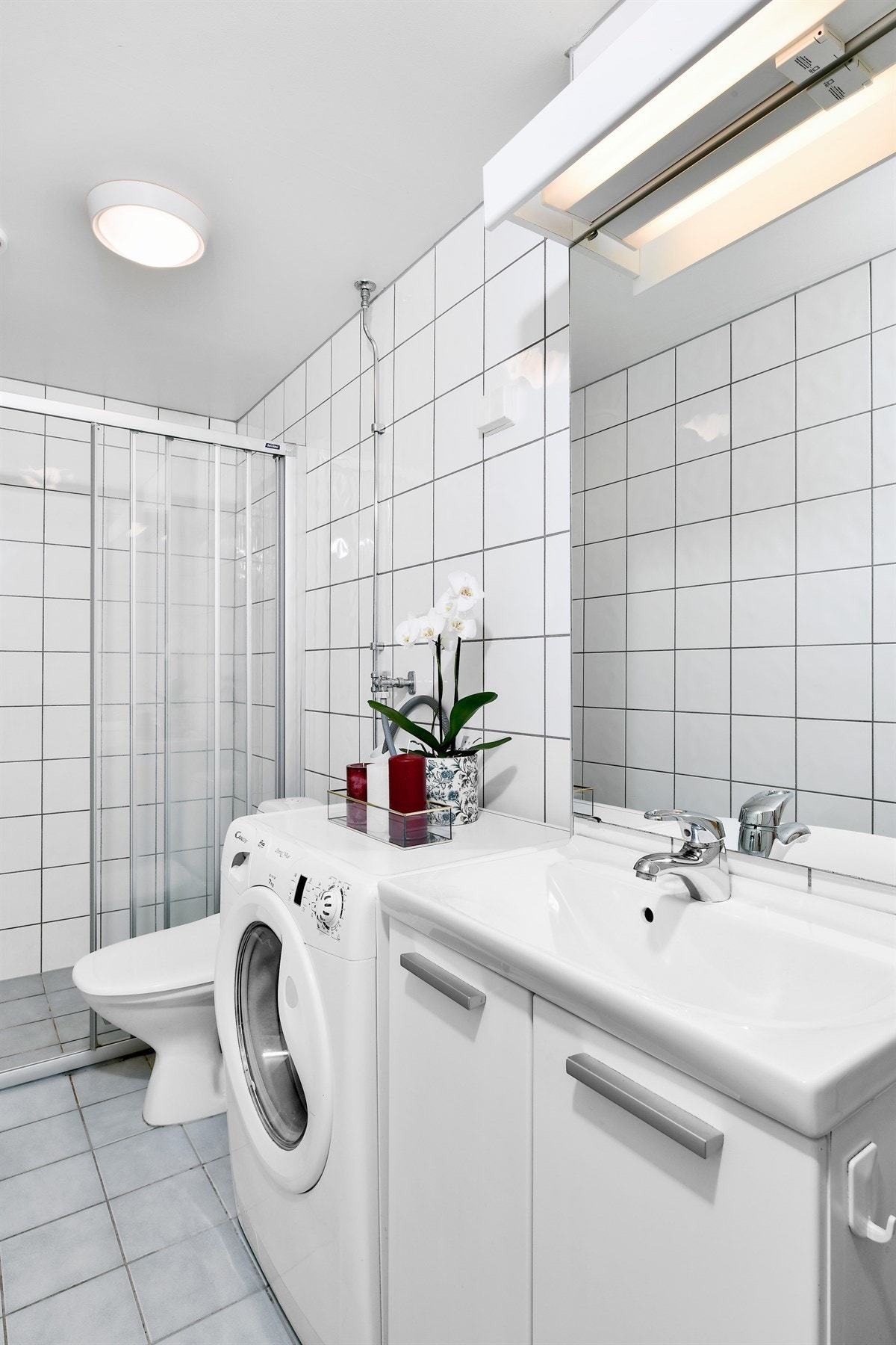 Badet er pent med grå gulvfliser, hvite veggfliser og gulvvarme. Galleribilde