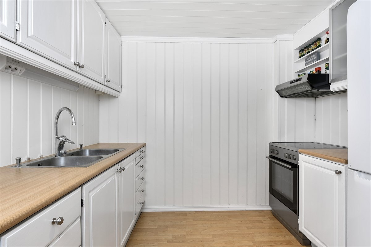 Innredningen har lyse, profilerte fronter, ventilator og en laminatbenkeplate med nedfelt dobbeltkum. Galleribilde