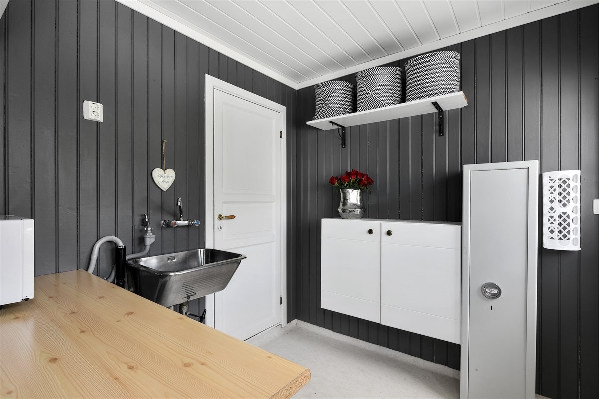 Rommet er praktisk innredet med veggskap, vegghylle og en benkeplate. Under benkeplate er det plass til både vaskemaskin og tørketrommel. Galleribilde