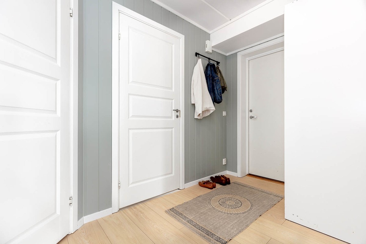 Inngangspartiet er stort og fint, med hvitmalte glatte overflater og gråmalte panelvegger. Galleribilde
