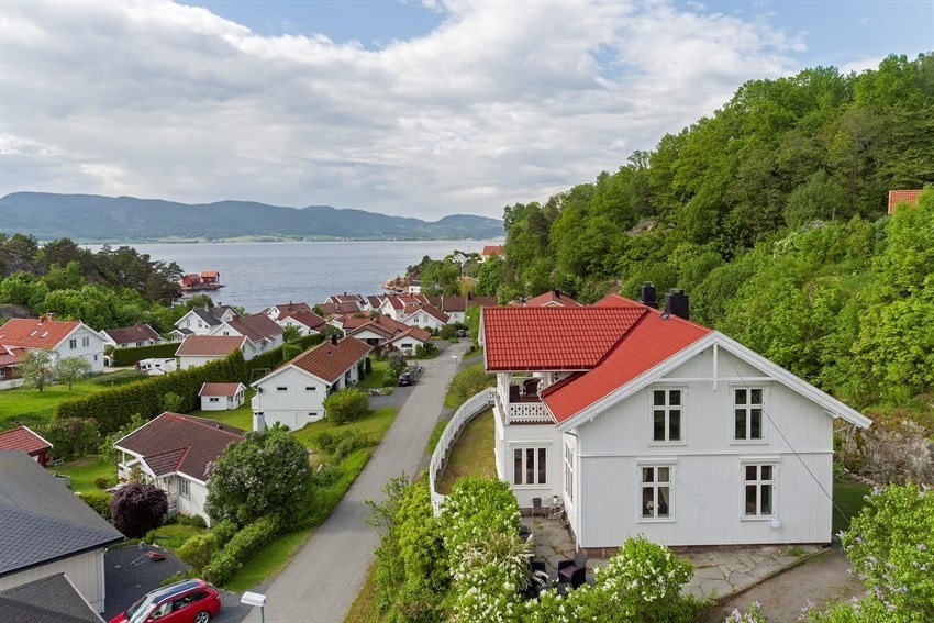 Villaen troner majestetisk i terrenget på en høytliggende tomt. Galleribilde