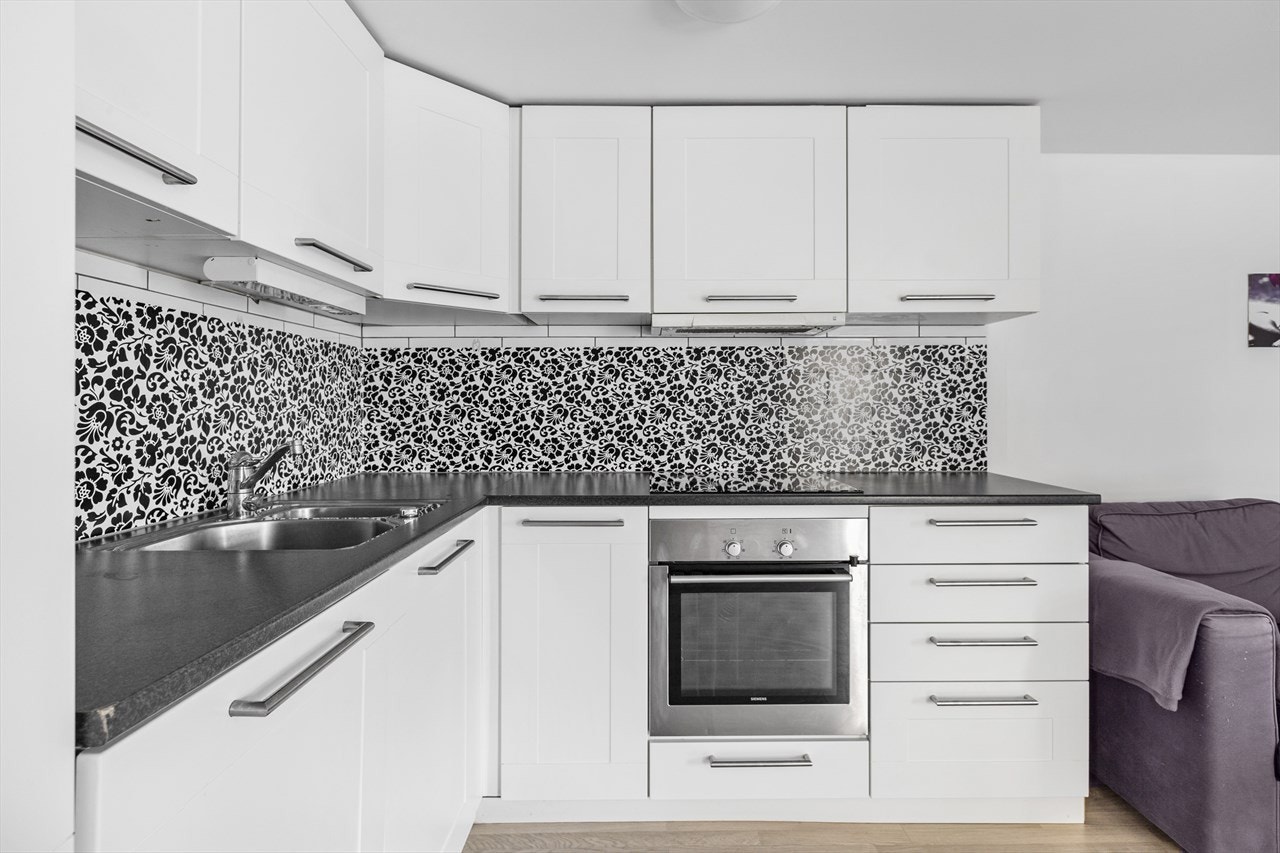 Hvit kjøkkeninnredning fra 2007 med laminat benkeplate og fliser mellom over og underskap Galleribilde