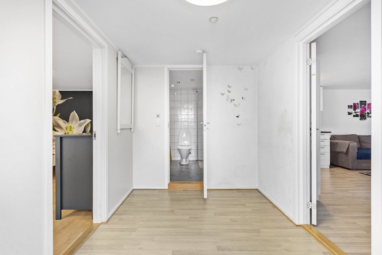 Boligen har et praktisk inngangsparti med parkett på gulv og lysmalte vegger Galleribilde