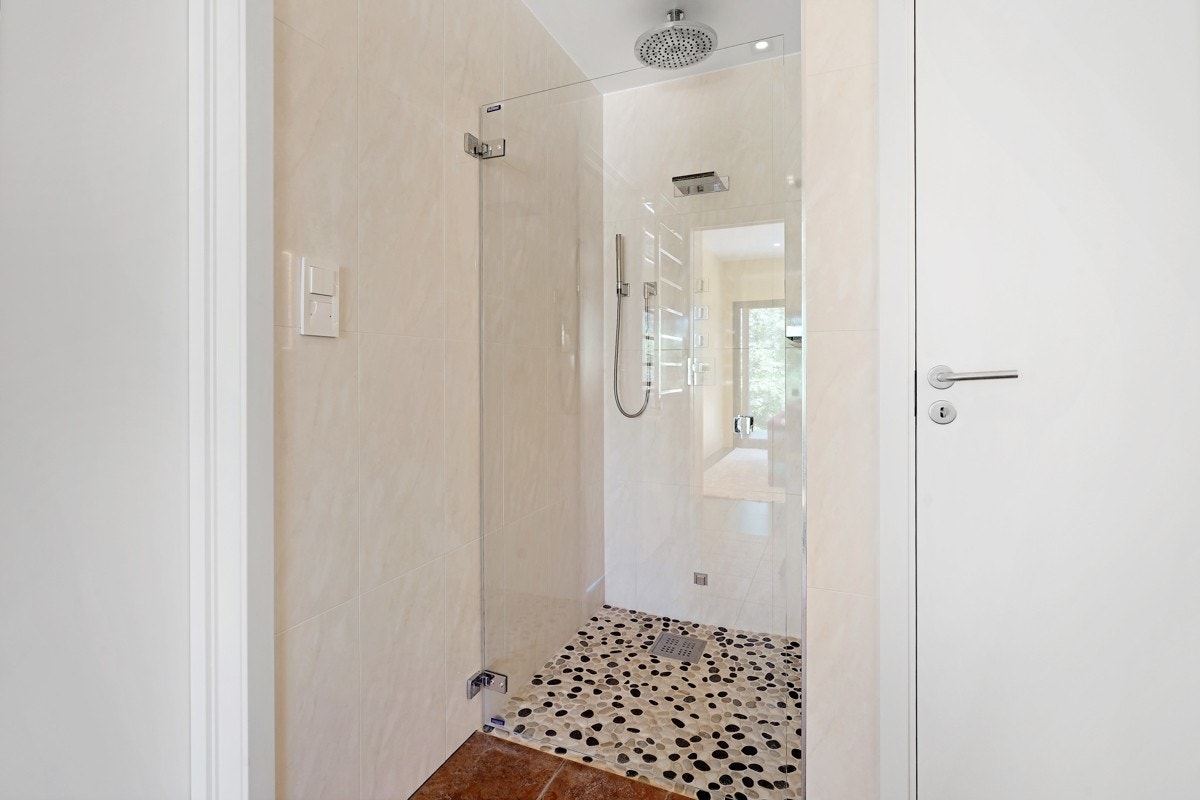 I dusjnisjen er det rullesteinsgulv, glassvegg, takmontert regnfallsdusj og en hånddusj. Galleribilde