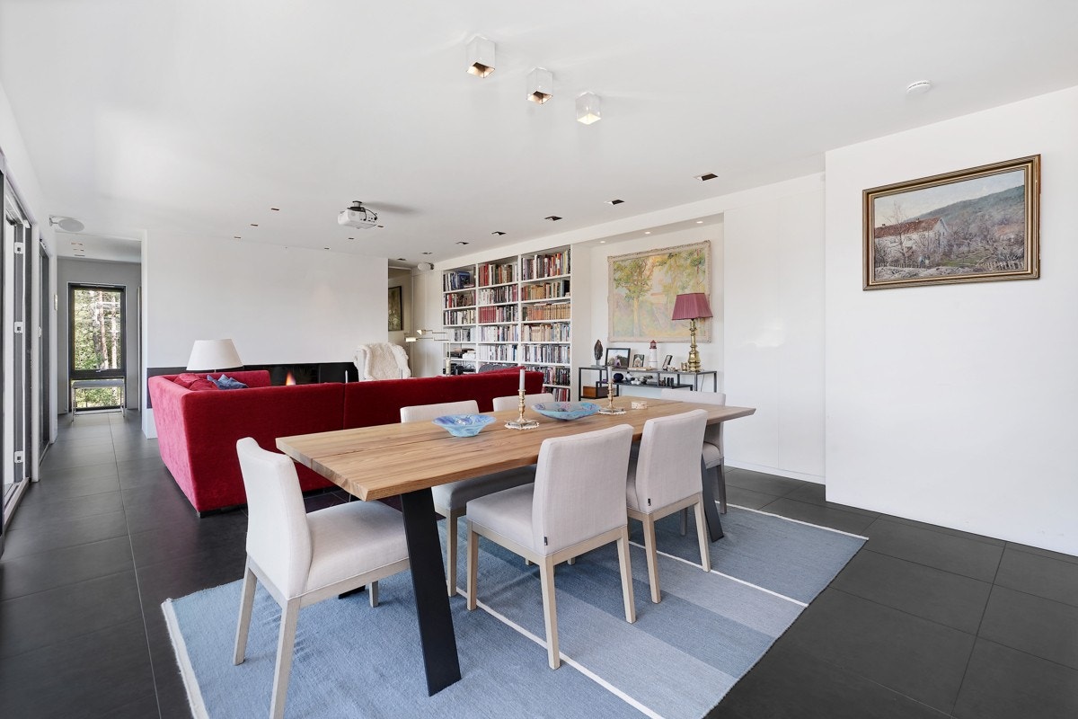 Stuen har hvitmalte vegger og mørke gulvfliser, i likhet med den andre stuen, og plassbygde bokhyller og skap langs én vegg. Galleribilde