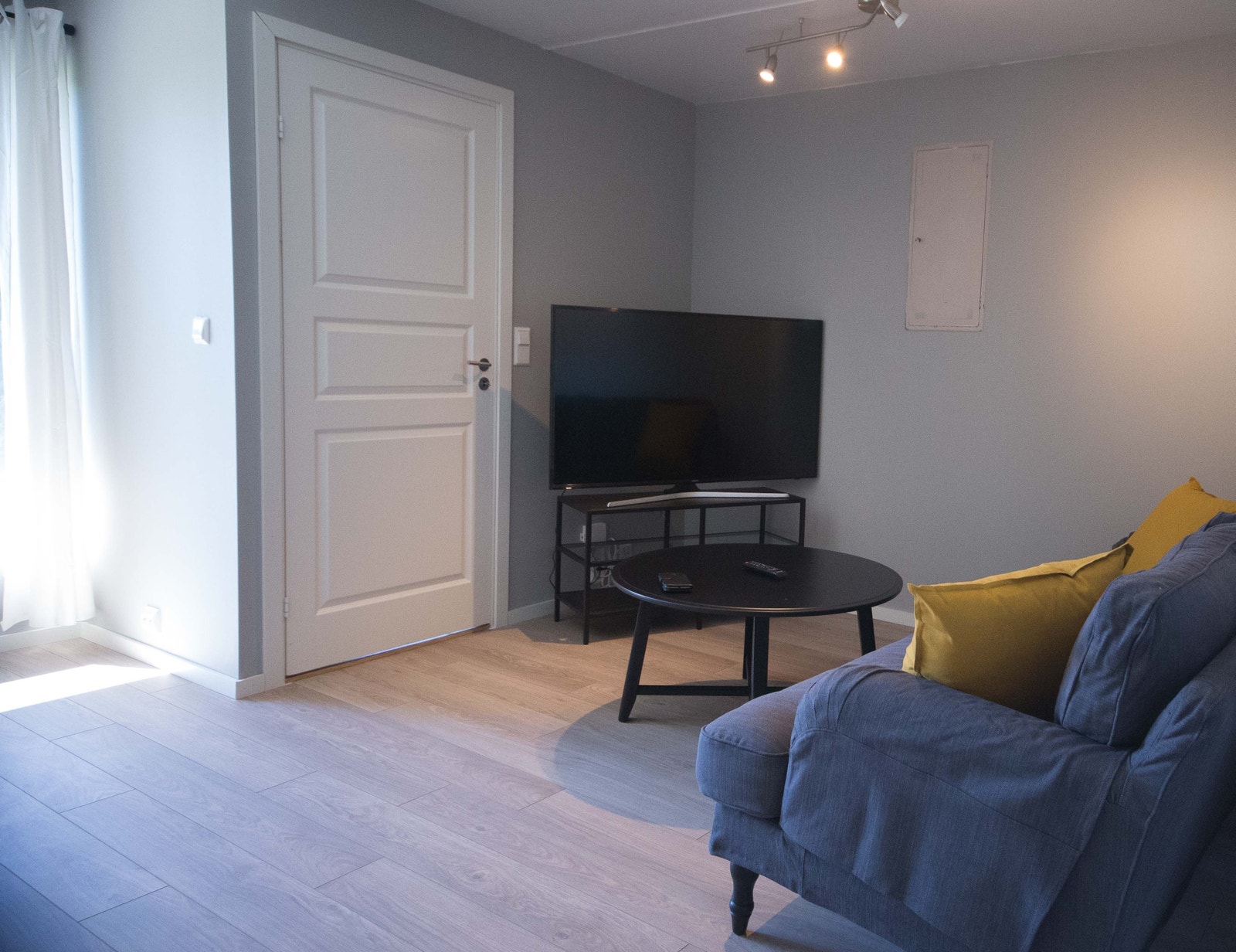En del av stuen med ny stor 55" TV, ny sofa og bord. Det er parkett med varmekabler i gulv. Galleribilde