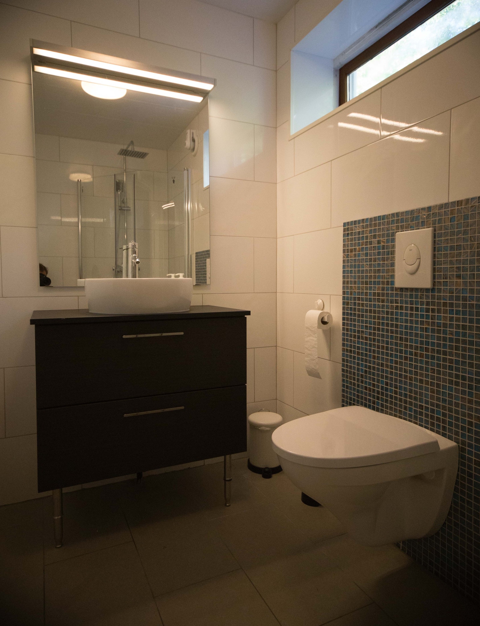 Badet med stor kommode under vasken. Med skapet til høyre for dusjen er det stor plass til oppbevaring. Galleribilde