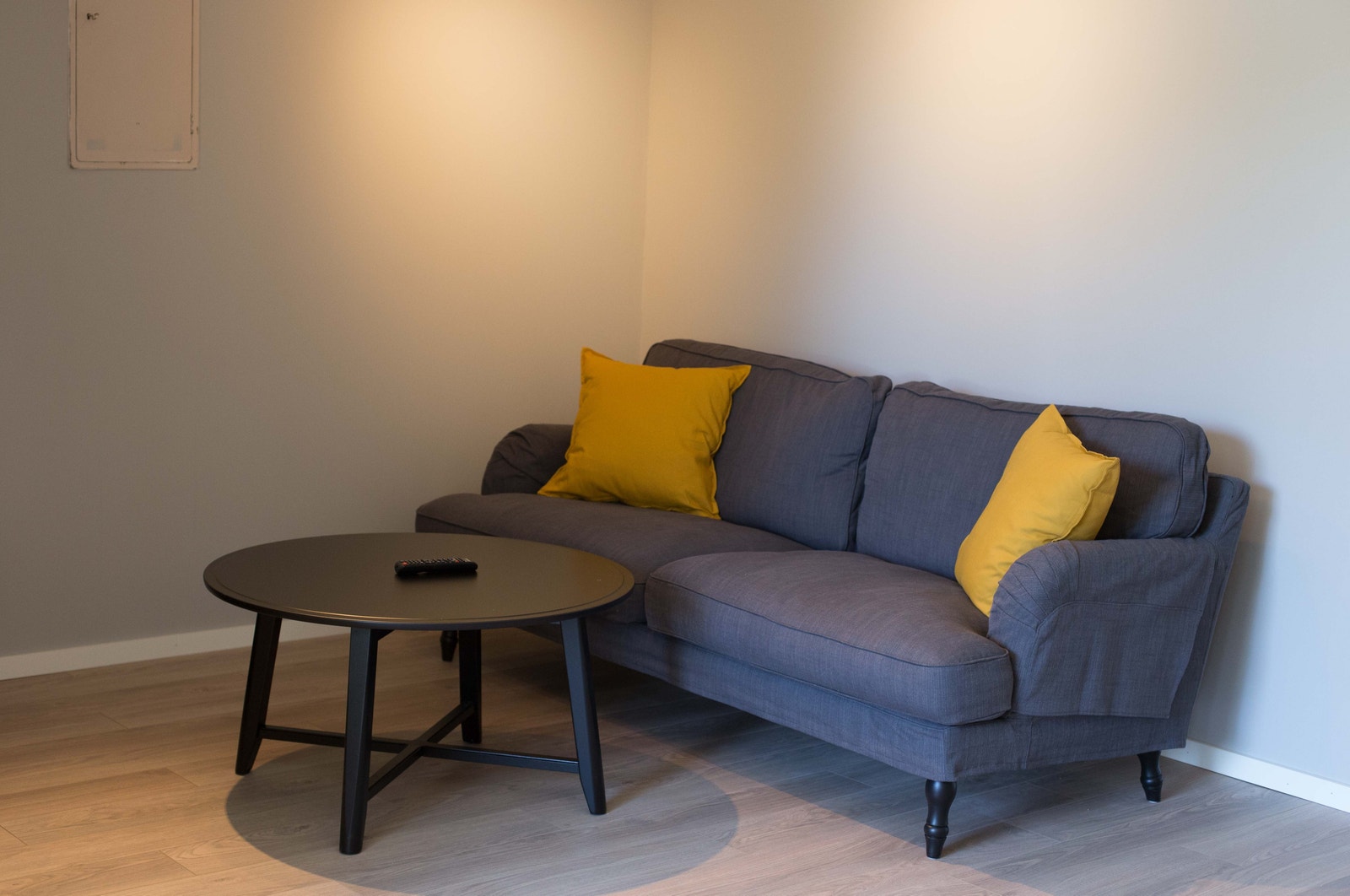 Studen med sofa og bord. En åpen stue og kjøkken løsning. Det er parkett med varmekabler i gulv Galleribilde