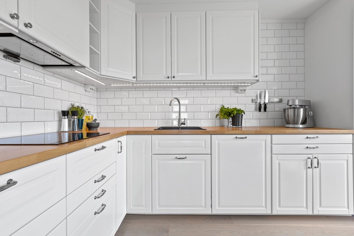Delikat kjøkken fra 2016 med hvite glatte fyllingfronter, eikefinert laminat benkeplater og flotte fliser over kjøkkenbenk Galleribilde