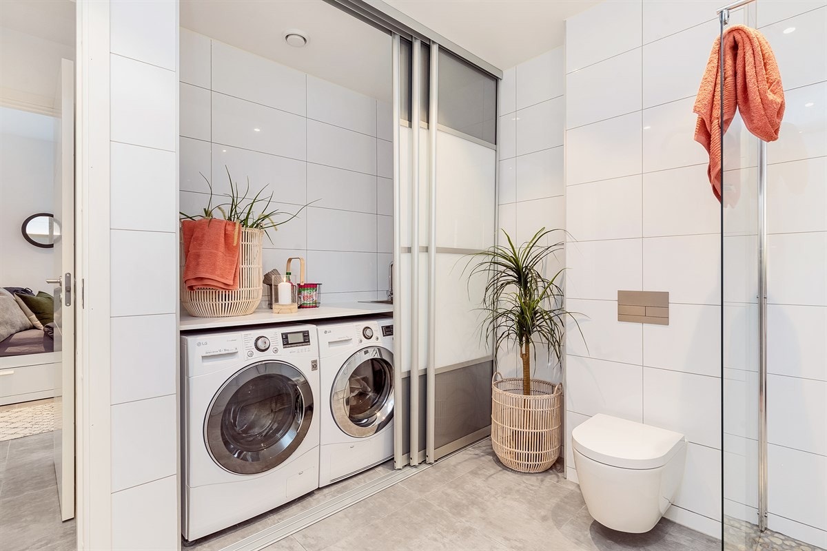 Skyvedører som avgrenser til nisje hvor man har vaskemaskin, tørketrommel, utslagsvask og benkeplate. Galleribilde