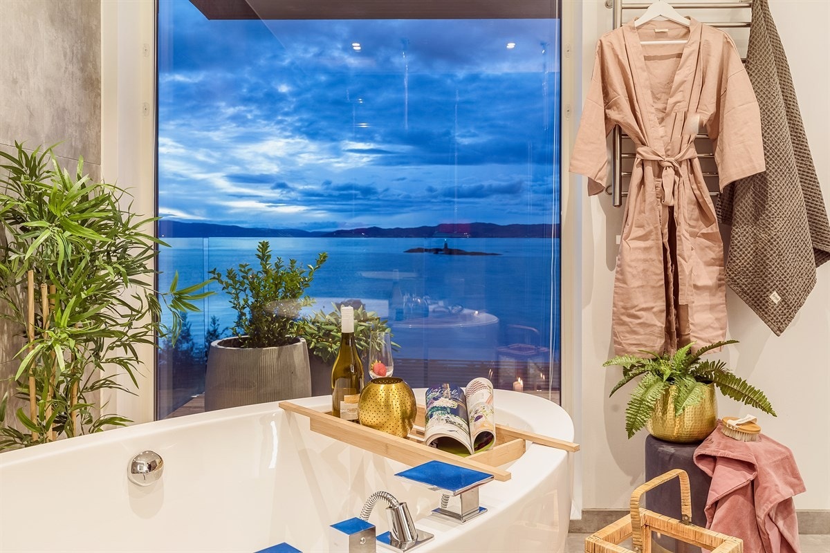 Her er dusjnisje med glassvegger og dobbeltdusj, badekar med nydelig fjordutsikt, vegghengt toalett og baderomsinnredning. Galleribilde