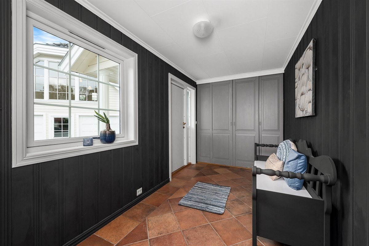 Entreen gir et godt og lunt førsteinntrykk med sortmalte panelvegger, gulvfliser og gulvvarme. Rommet har garderobe med grå fronter og god plass for andre entrémøbler. Galleribilde