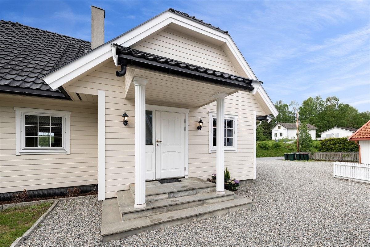 Boligens inngangsparti har et pent overbygg hvilende på søyler. Galleribilde